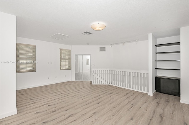 spare room featuring light hardwood / wood-style flooring and a textured ceiling