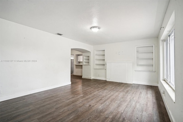 empty room featuring dark hardwood / wood-style flooring and built in features