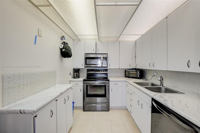 kitchen with white cabinetry, tasteful backsplash, light tile patterned floors, stainless steel appliances, and sink