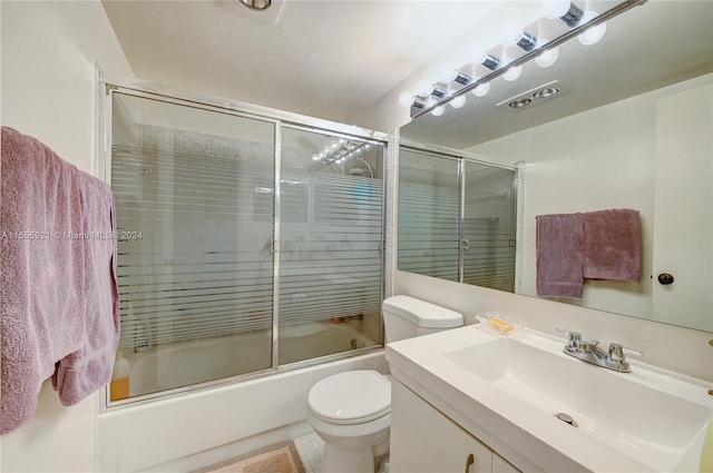 full bathroom featuring enclosed tub / shower combo, vanity, and toilet