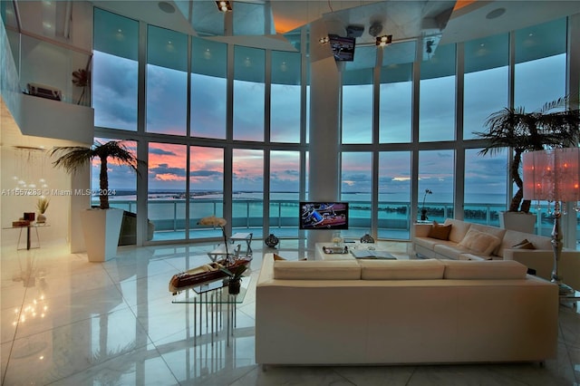 tiled living room featuring a water view, a wall of windows, and a towering ceiling