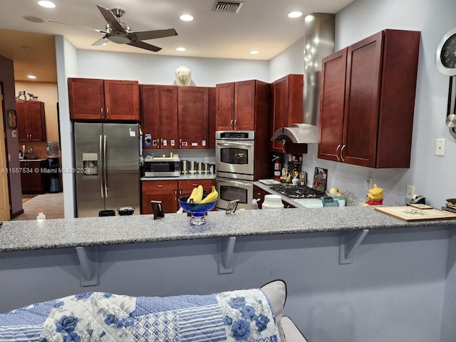 kitchen with range hood, stainless steel appliances, ceiling fan, and a breakfast bar