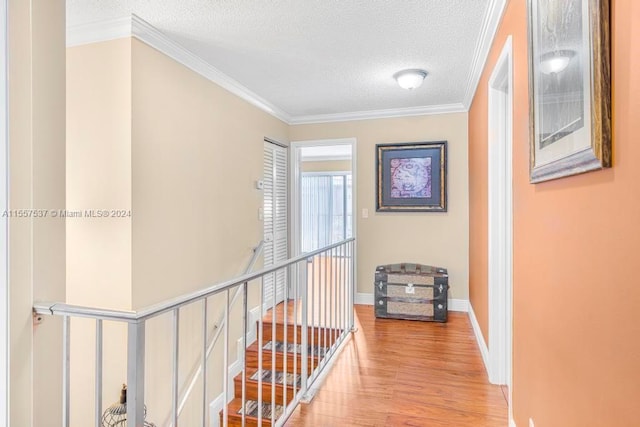 hall featuring light hardwood / wood-style floors, a textured ceiling, and crown molding