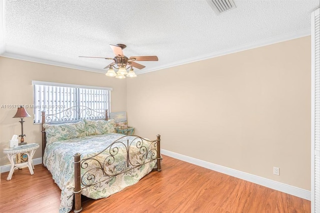 bedroom featuring ornamental molding, a textured ceiling, ceiling fan, and light wood-type flooring