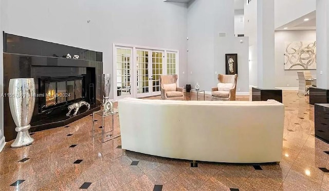 living room featuring light tile floors, french doors, and a high ceiling