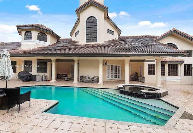 back of property featuring a patio and a swimming pool with hot tub