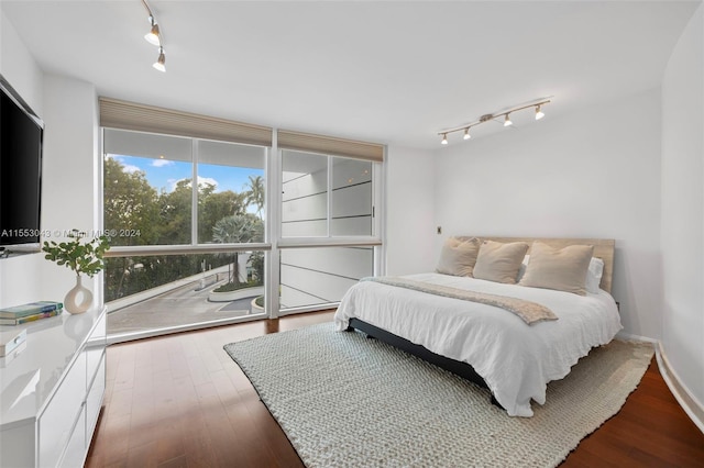 bedroom with rail lighting and light wood-type flooring