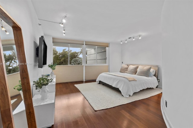 bedroom featuring track lighting and dark wood-type flooring