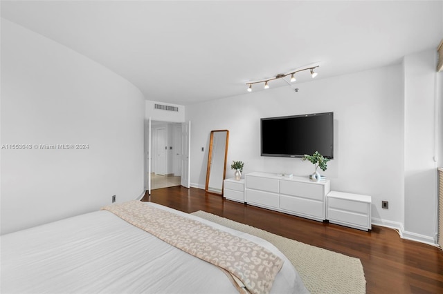 bedroom with rail lighting and dark hardwood / wood-style floors