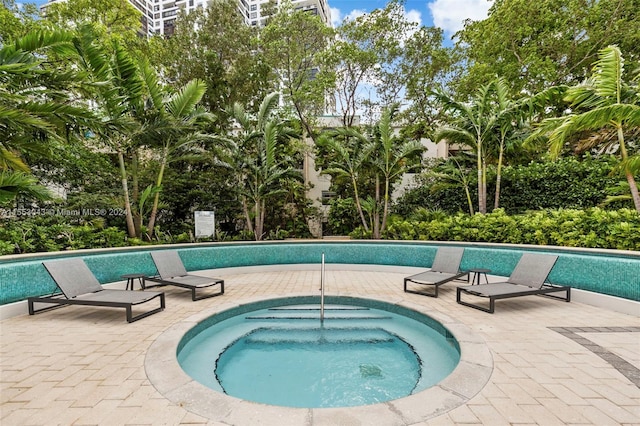 view of pool with a hot tub and a patio