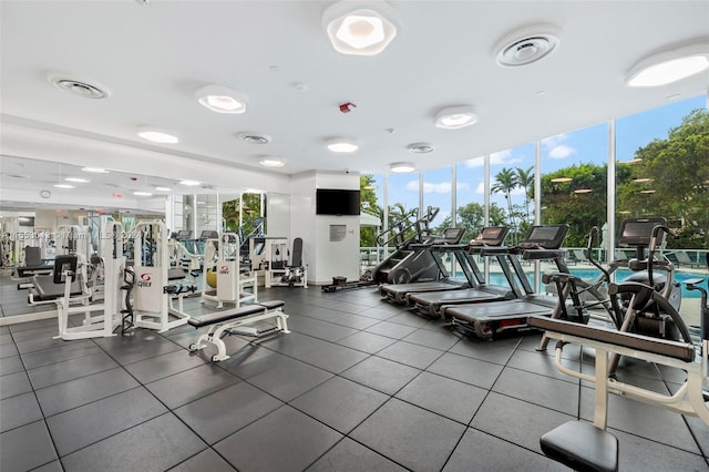 gym featuring a wall of windows and dark tile floors