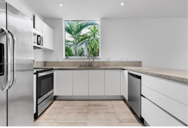 kitchen featuring white cabinetry, light stone counters, stainless steel appliances, and sink