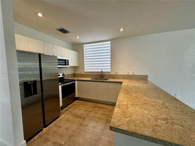 kitchen with white cabinetry, sink, stainless steel dishwasher, and light stone countertops