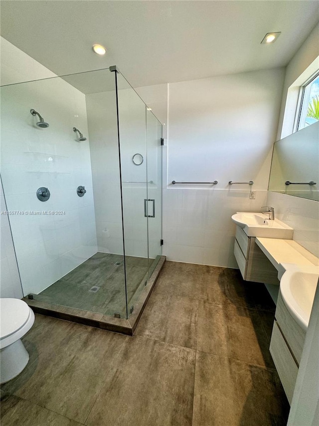 bathroom featuring vanity, toilet, an enclosed shower, and tile walls