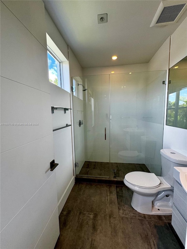 bathroom with a shower with door, vanity, and toilet