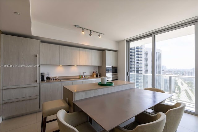 kitchen featuring light brown cabinets, light tile floors, a center island, track lighting, and sink