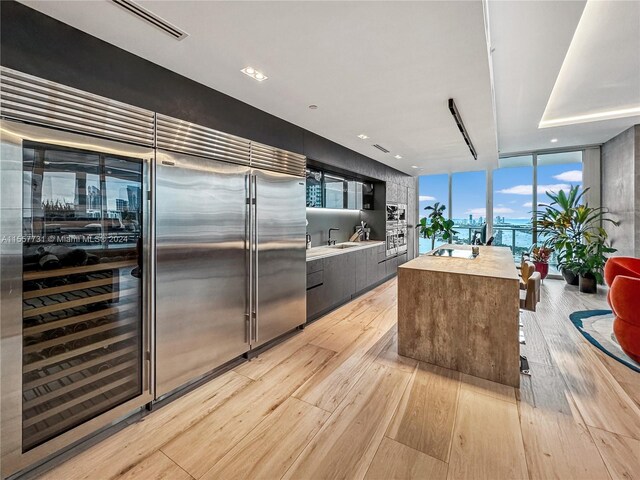 kitchen with light wood-type flooring, a wall of windows, built in refrigerator, and butcher block countertops