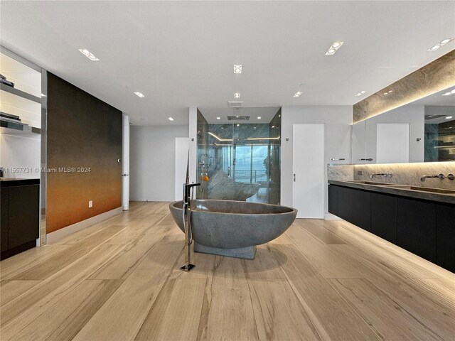 interior space with tasteful backsplash, sink, and light hardwood / wood-style floors