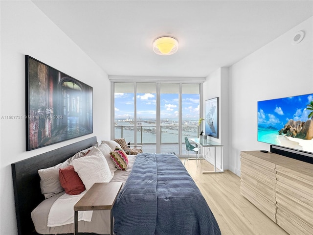 bedroom featuring a wall of windows and light hardwood / wood-style floors