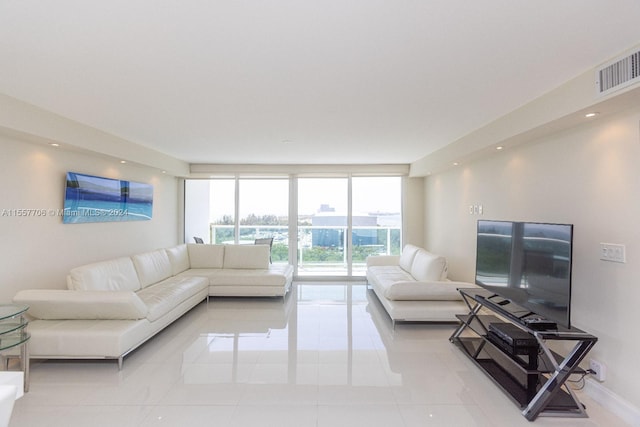 living room with light tile flooring and a wall of windows