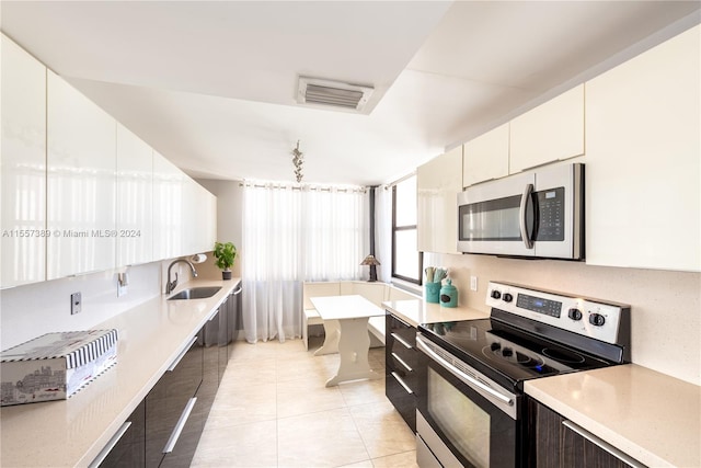 kitchen featuring white cabinets, light tile flooring, sink, and stainless steel appliances