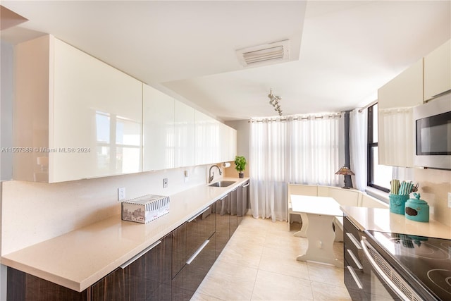 kitchen with light tile flooring, sink, a breakfast bar, and white cabinets