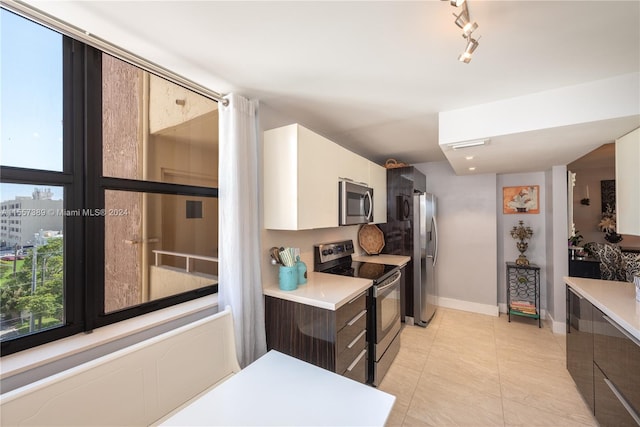 kitchen with stainless steel appliances, light tile flooring, white cabinetry, and track lighting