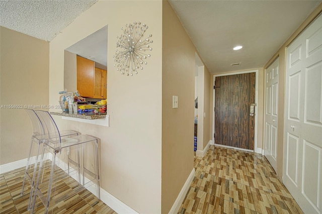 hallway with a textured ceiling and light hardwood / wood-style floors