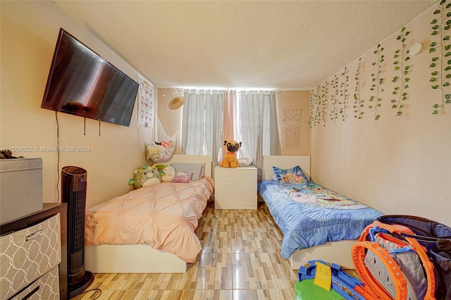 bedroom with a textured ceiling and light hardwood / wood-style floors