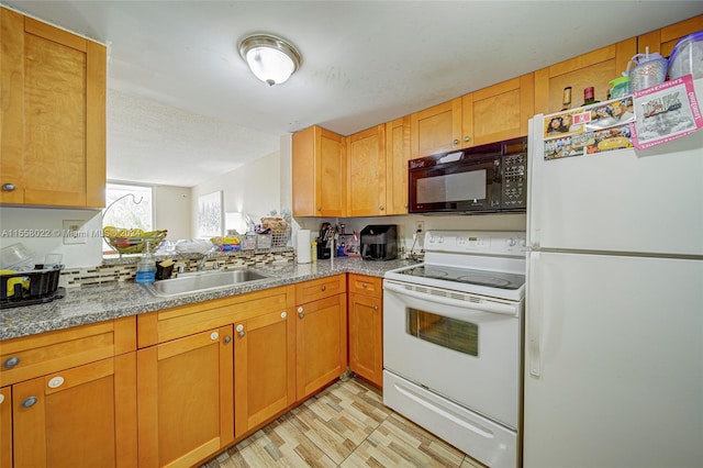 kitchen featuring white appliances, sink, and light stone countertops