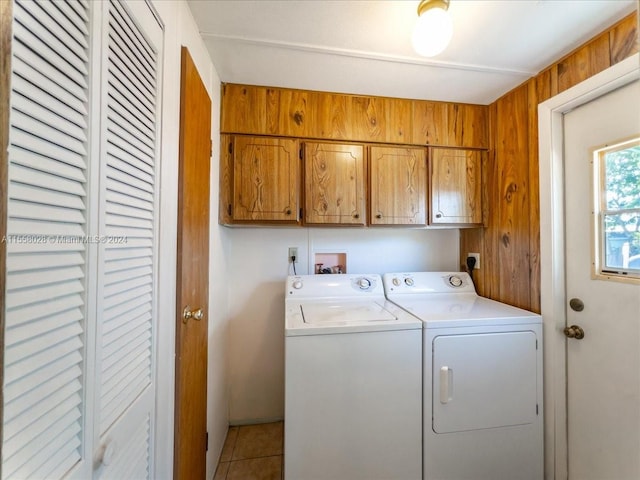 washroom featuring cabinets, light tile floors, washer and clothes dryer, wood walls, and washer hookup