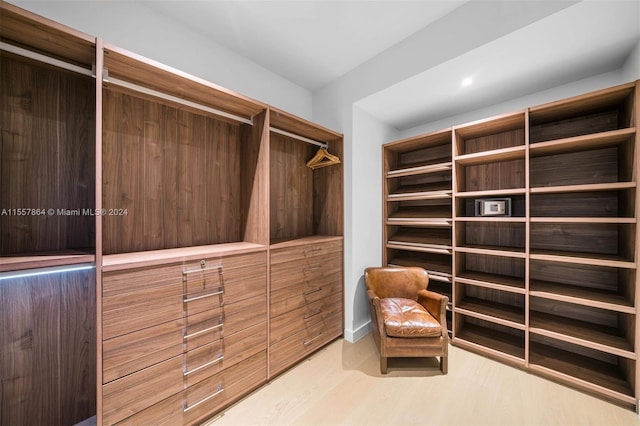 walk in closet with light hardwood / wood-style floors