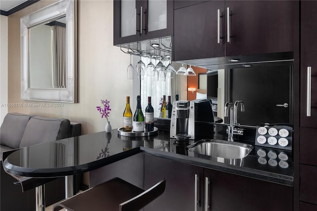 kitchen with dark brown cabinetry, dark stone counters, sink, and ornamental molding