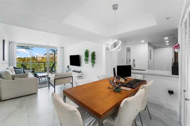 dining room featuring a raised ceiling, an inviting chandelier, sink, and light tile floors