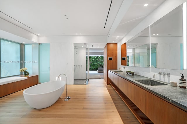 bathroom with double vanity, backsplash, a bath, and hardwood / wood-style floors