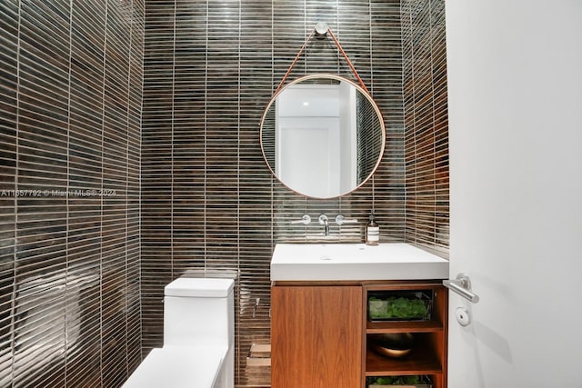 bathroom with tile walls, toilet, and vanity