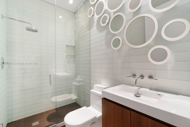 bathroom featuring vanity, a shower with door, tile walls, and toilet