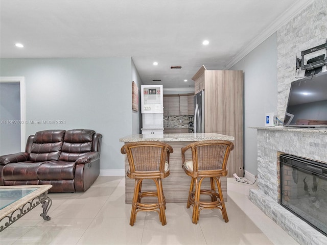 dining area with ornamental molding, a stone fireplace, and light tile floors