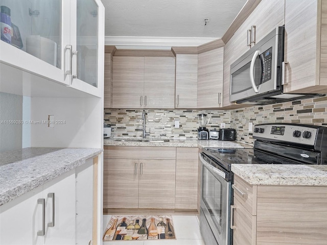 kitchen with sink, light stone counters, appliances with stainless steel finishes, tasteful backsplash, and light brown cabinets