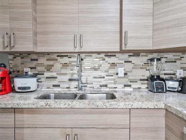 kitchen featuring backsplash, sink, and light stone counters