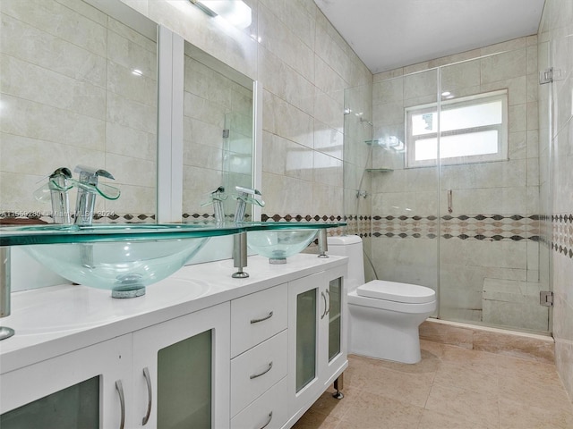 bathroom featuring tile walls, walk in shower, toilet, dual vanity, and tile flooring