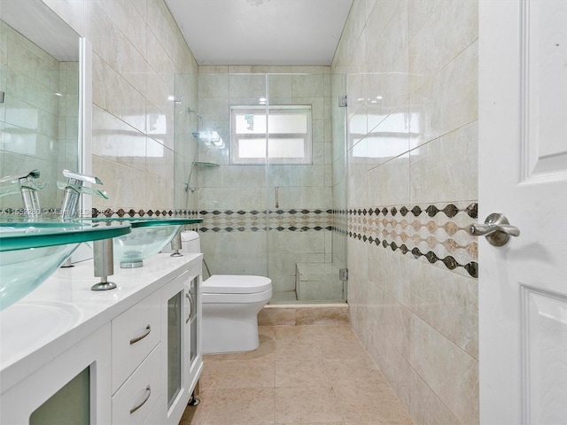 bathroom with toilet, a shower with door, tile walls, dual bowl vanity, and tile flooring