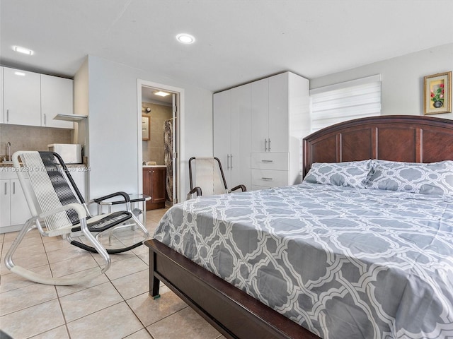 bedroom with connected bathroom and light tile flooring