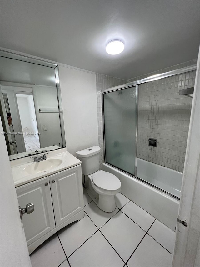 full bathroom featuring toilet, tile floors, vanity, and bath / shower combo with glass door