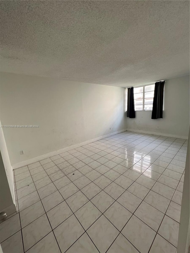 tiled spare room with a textured ceiling