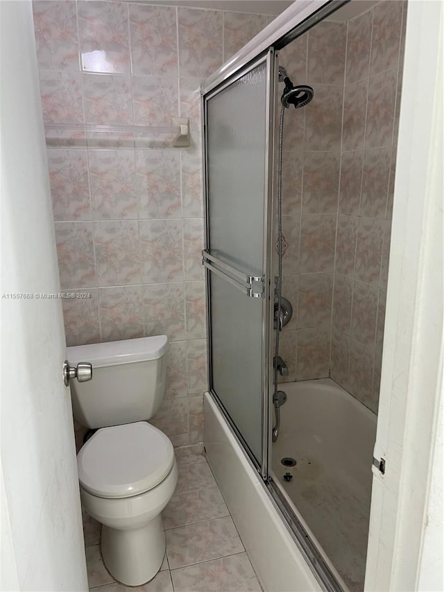 bathroom featuring enclosed tub / shower combo, tile walls, tile floors, and toilet