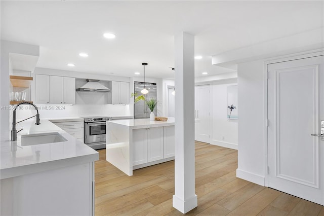 kitchen featuring pendant lighting, sink, stainless steel range with electric cooktop, white cabinetry, and light hardwood / wood-style flooring