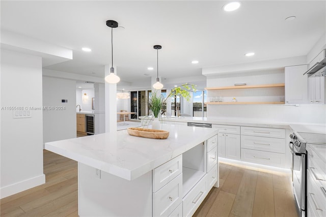 kitchen with light hardwood / wood-style floors, white cabinetry, electric stove, a kitchen island, and light stone countertops