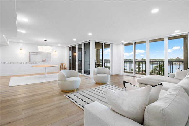 living room featuring light wood-type flooring, a water view, and wood walls