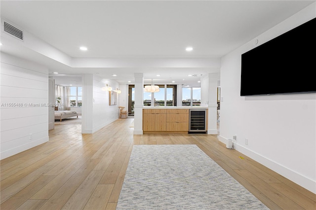 interior space with beverage cooler, light hardwood / wood-style floors, light brown cabinets, and decorative light fixtures